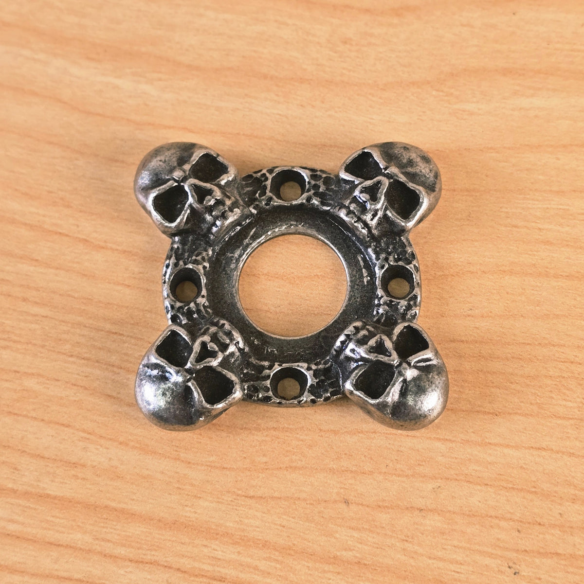Top view of cast metal skull motif guitar part on wood surface
