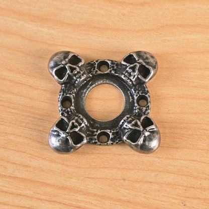 Top view of cast metal skull motif guitar part on wood surface