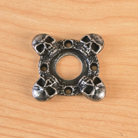 Top view of cast metal skull motif guitar part on wood surface