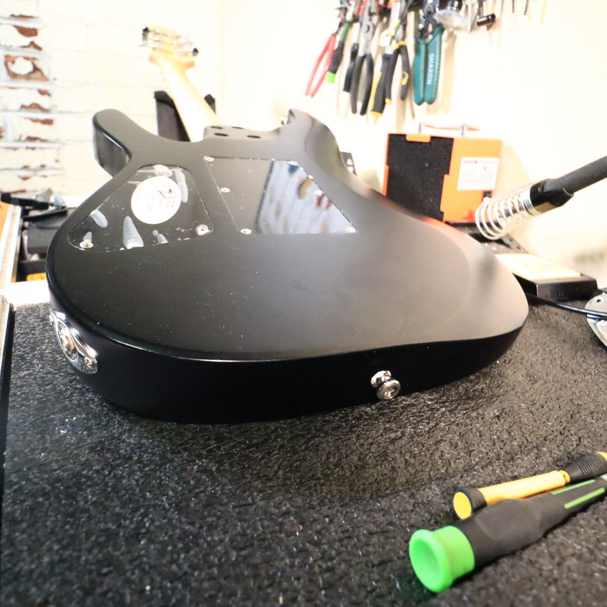 Bottom end view of the guitar body on a workbench showing the strap button.