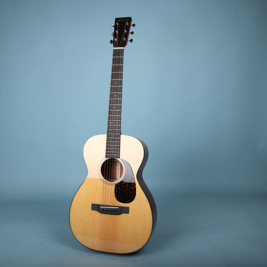 Full front view of the Martin 0-18 acoustic guitar standing against a light blue backdrop.