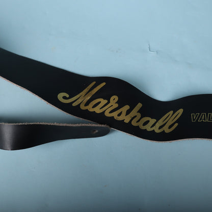 Close-up view of the gold Marshall script logo on the black leather guitar strap