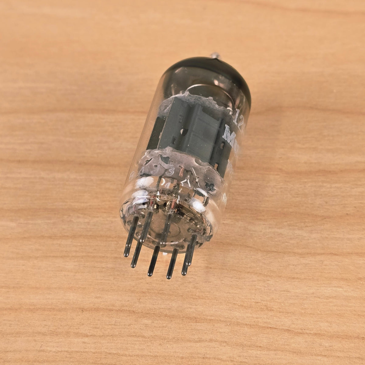 Bottom-angled view of Mullard 12AX7A vacuum tube showing 9-pin base construction.