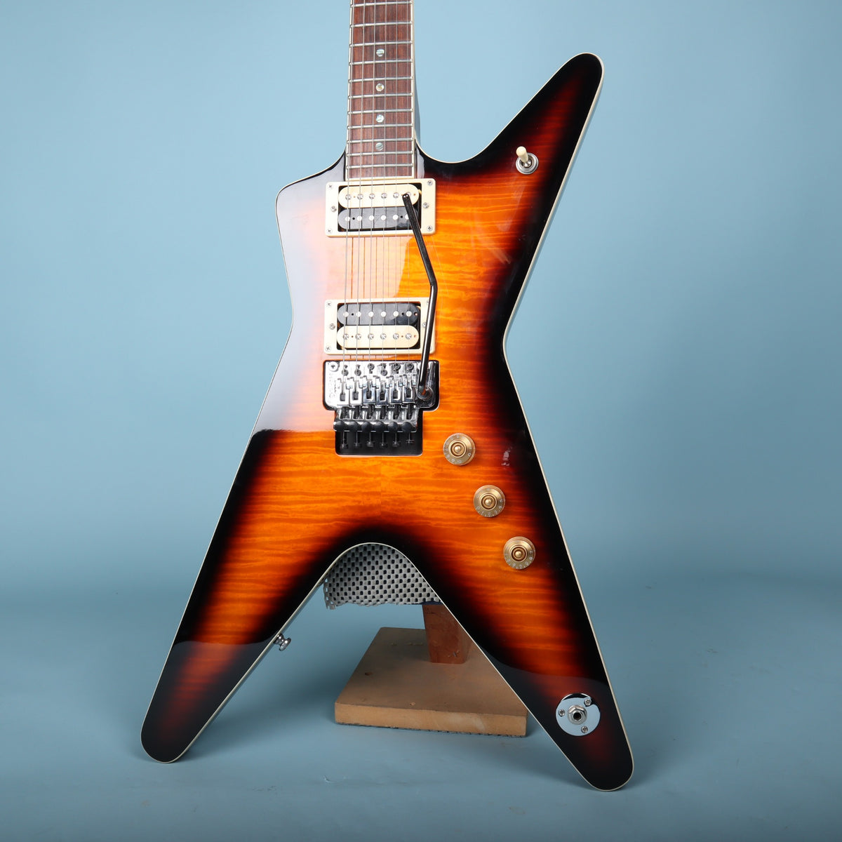 Dean ML electric guitar lower body on stand showing sunburst finish and Floyd Rose bridge
