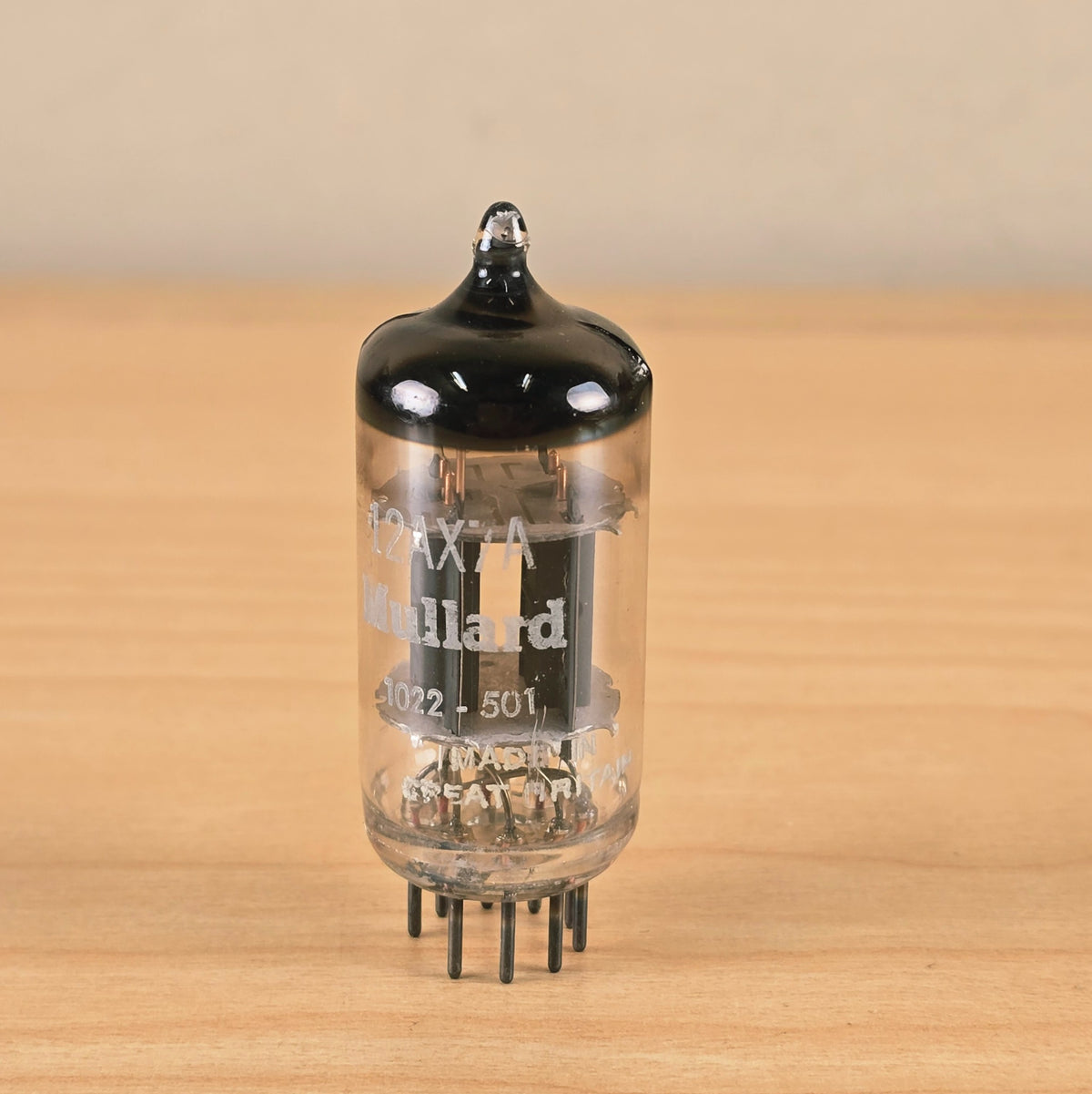 Straight-on view of Mullard 12AX7A vacuum tube standing upright.