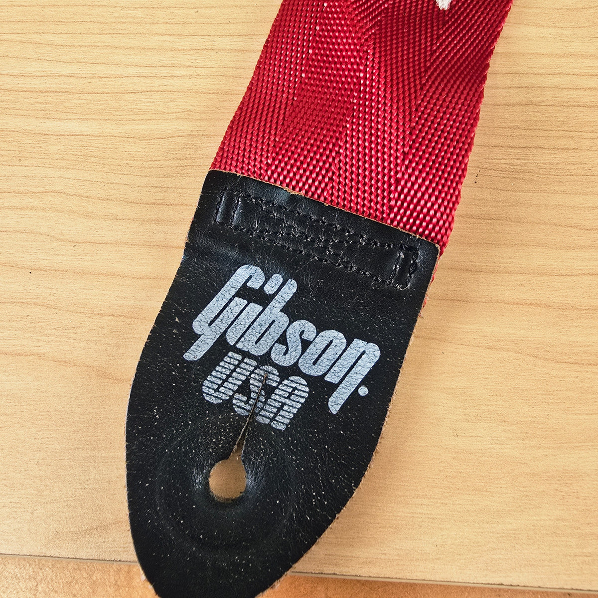 Close up view of the Gibson USA logo and leather stitch detail on the strap end