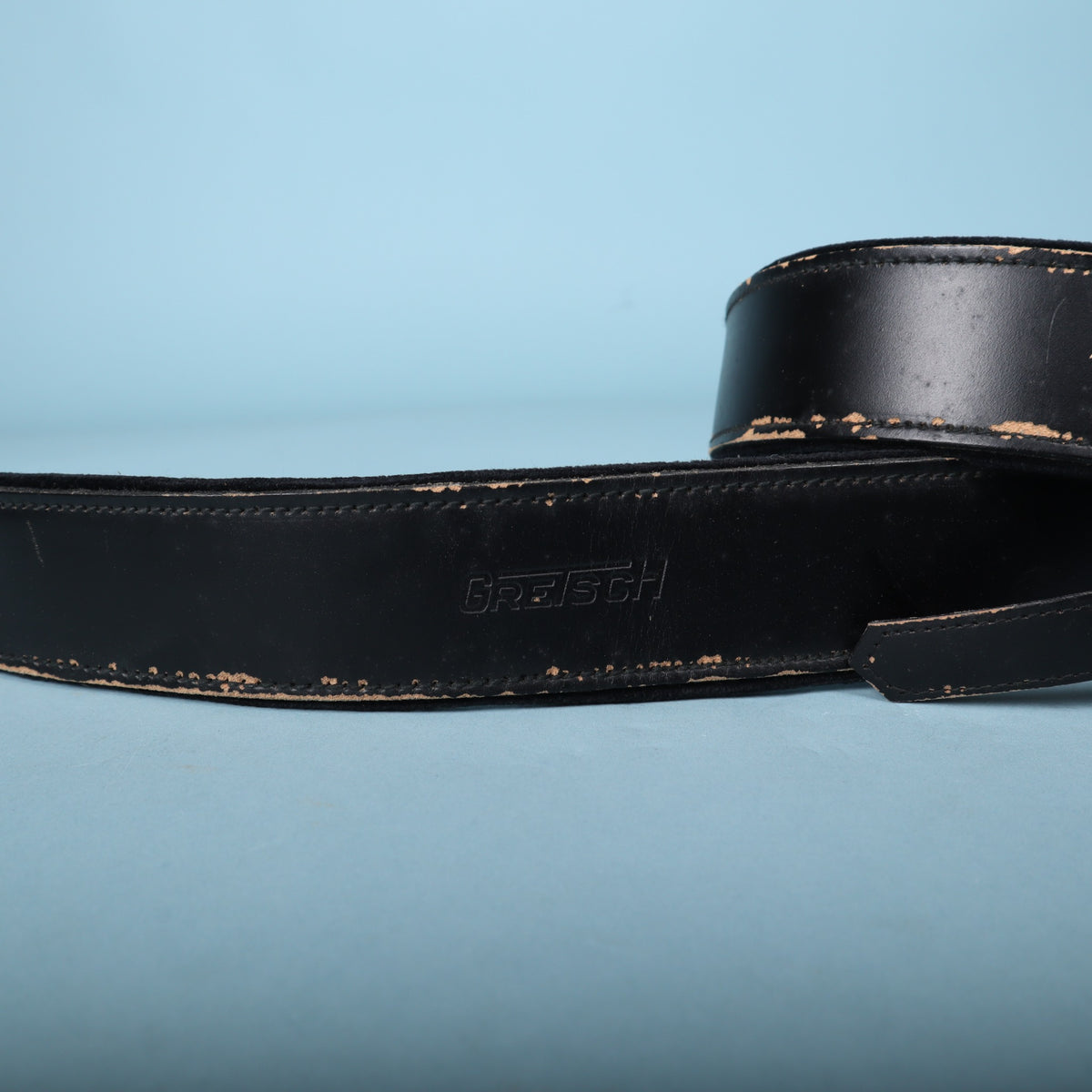 Close-up of embossed Gretsch logo on black leather strap.