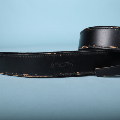 Close-up of embossed Gretsch logo on black leather strap.