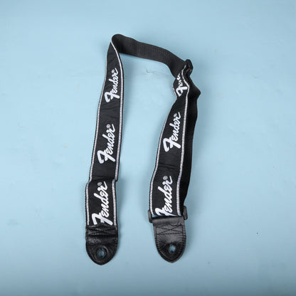 Fender running logo guitar strap laid out showing repeating white logos and leather ends