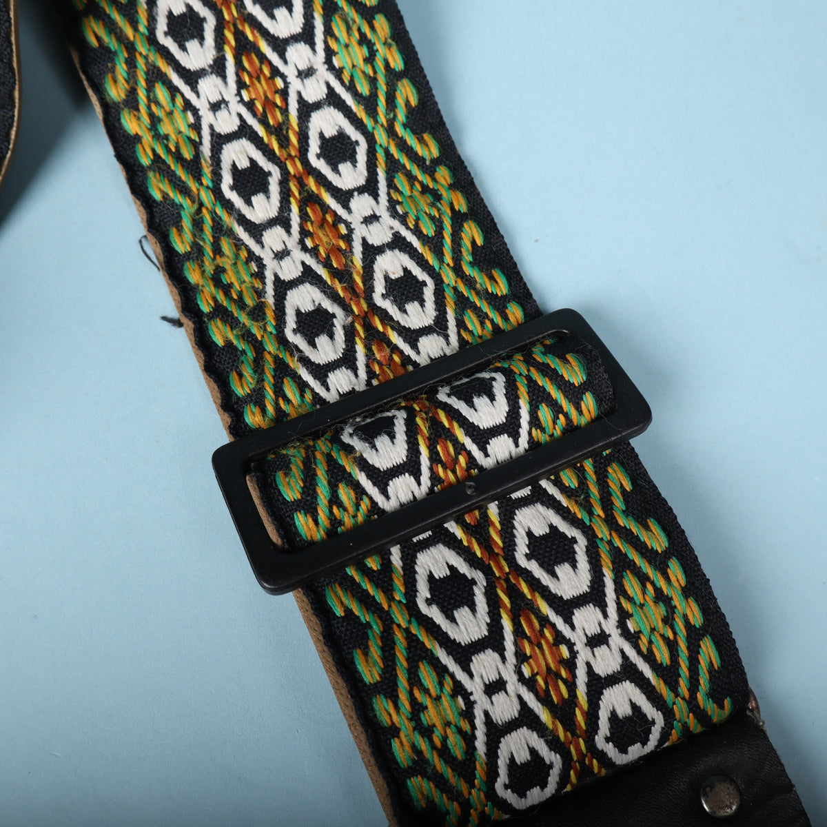 Close-up of the black plastic adjustment buckle on the woven jacquard strap.