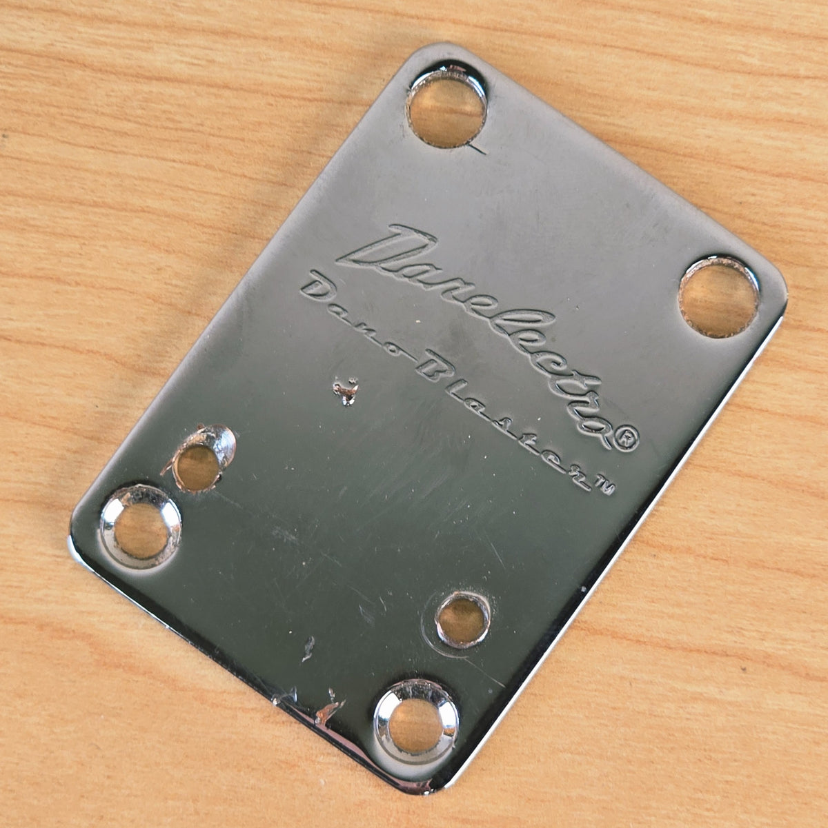 Top-down view of the chrome Danelectro Dano-Blaster guitar neck plate.