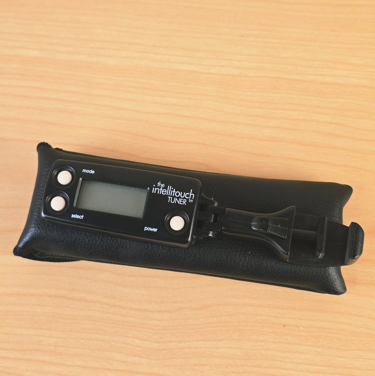 Angled view of The Intellitouch Tuner resting on top of its protective pouch.