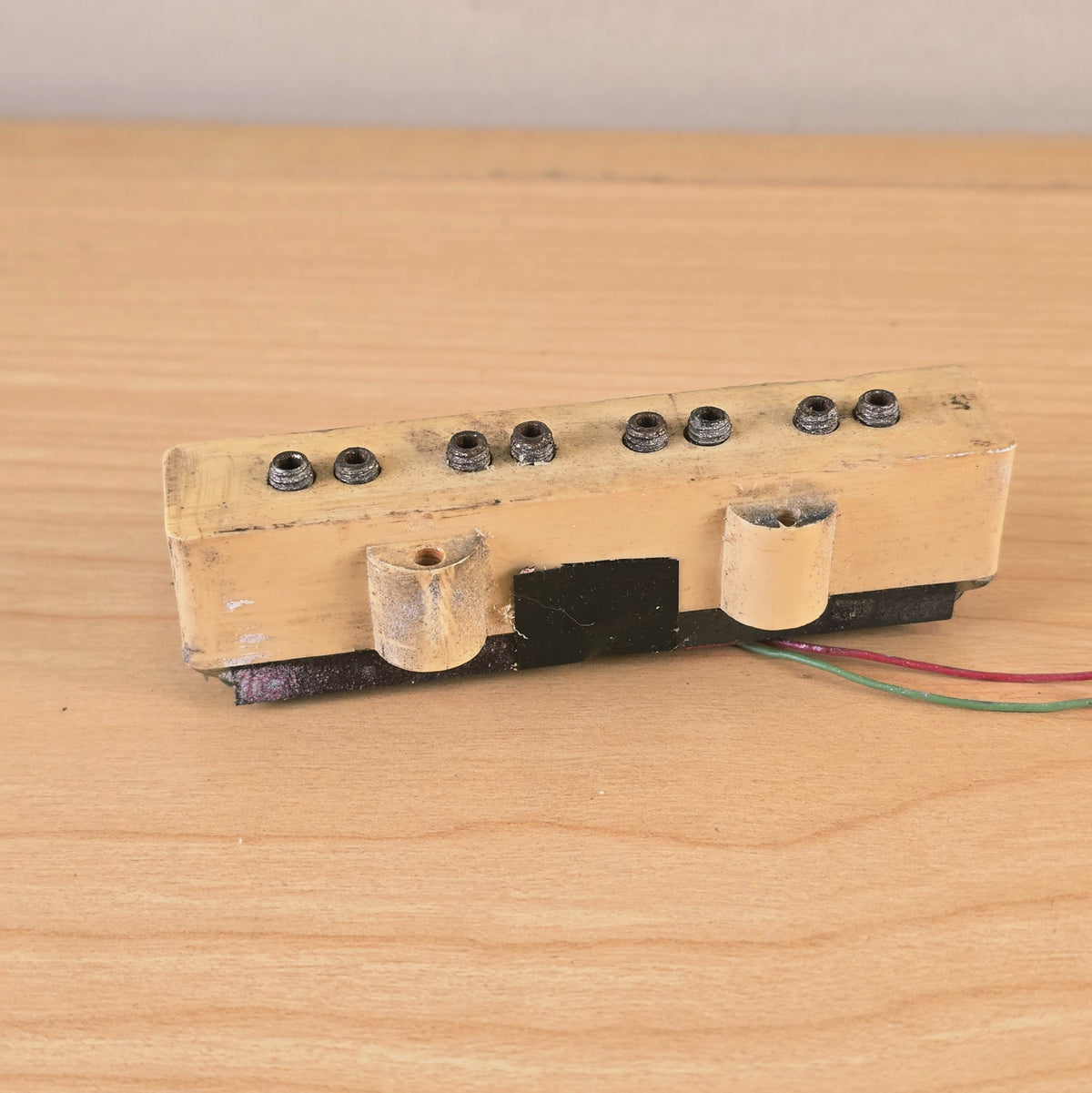 Side view of cream bass pickup showing mounting tabs and lower housing.