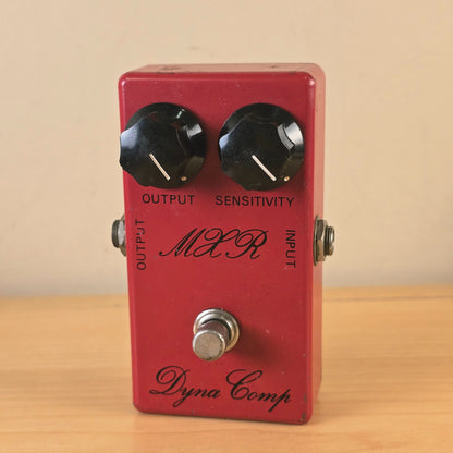 Front full view of a vintage 1970s MXR Dyna Comp script logo compressor pedal in red finish.