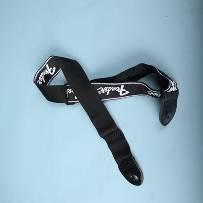 Full view of the coiled black Fender running logo guitar strap showing the underside and leather ends
