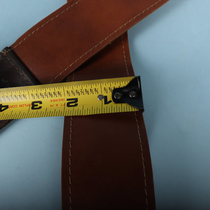 Close-up of a tape measure showing the Doctor Song leather guitar strap width at approximately 2.5 inches.