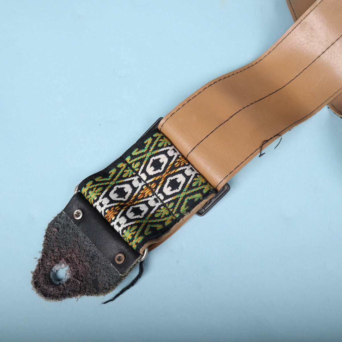 Detail of the buckle connector joining the tan vinyl section to the jacquard woven strap.