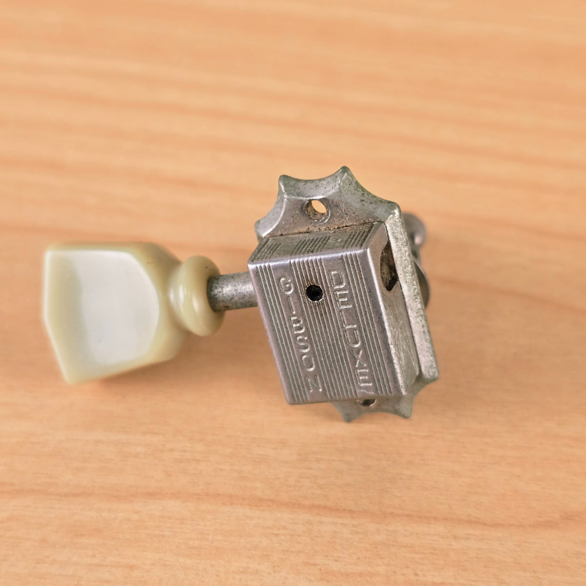 Close-up angled view of the stamped Gibson Deluxe tuner housing.