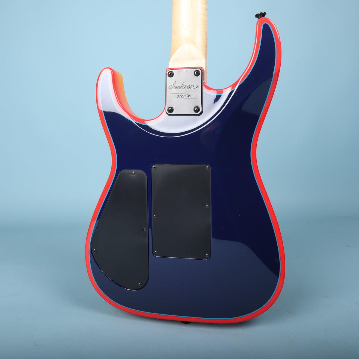 Rear view of dark blue guitar body showing black neck plate stamped 9727134