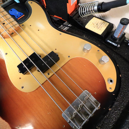 Overhead view of the bass body on a workbench showing bridge, pickup, and controls.