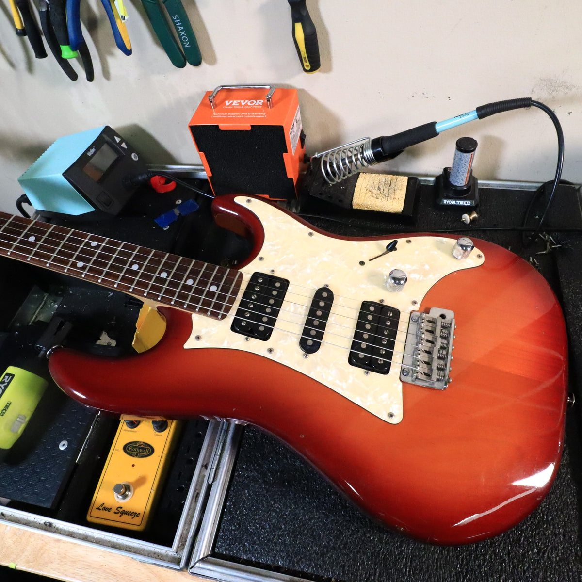 Close-up shot of headstock with Ibanez Blazer logo in workshop environment.