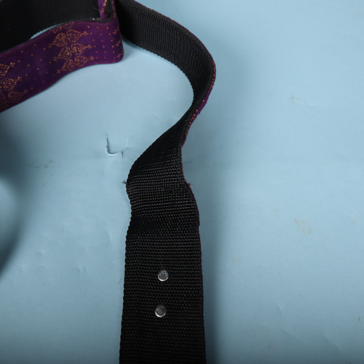 Close-up of the metal rivets reinforcing the black webbing strap back