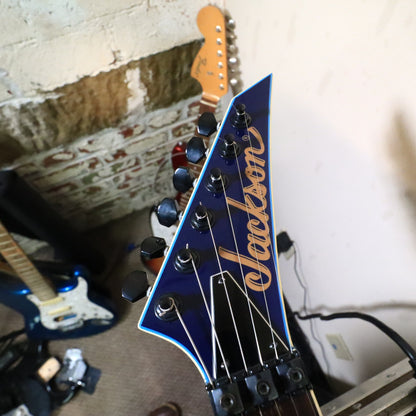 Headstock resting on bench showing Jackson logo and locking nut assembly
