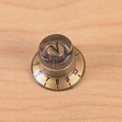 Top view of gold and transparent top hat knob with V marker on wooden surface