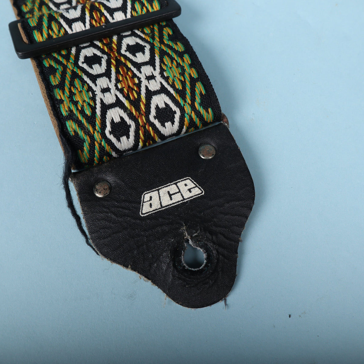 Close-up of the black leather end tab featuring the embossed white 1970s Ace logo.