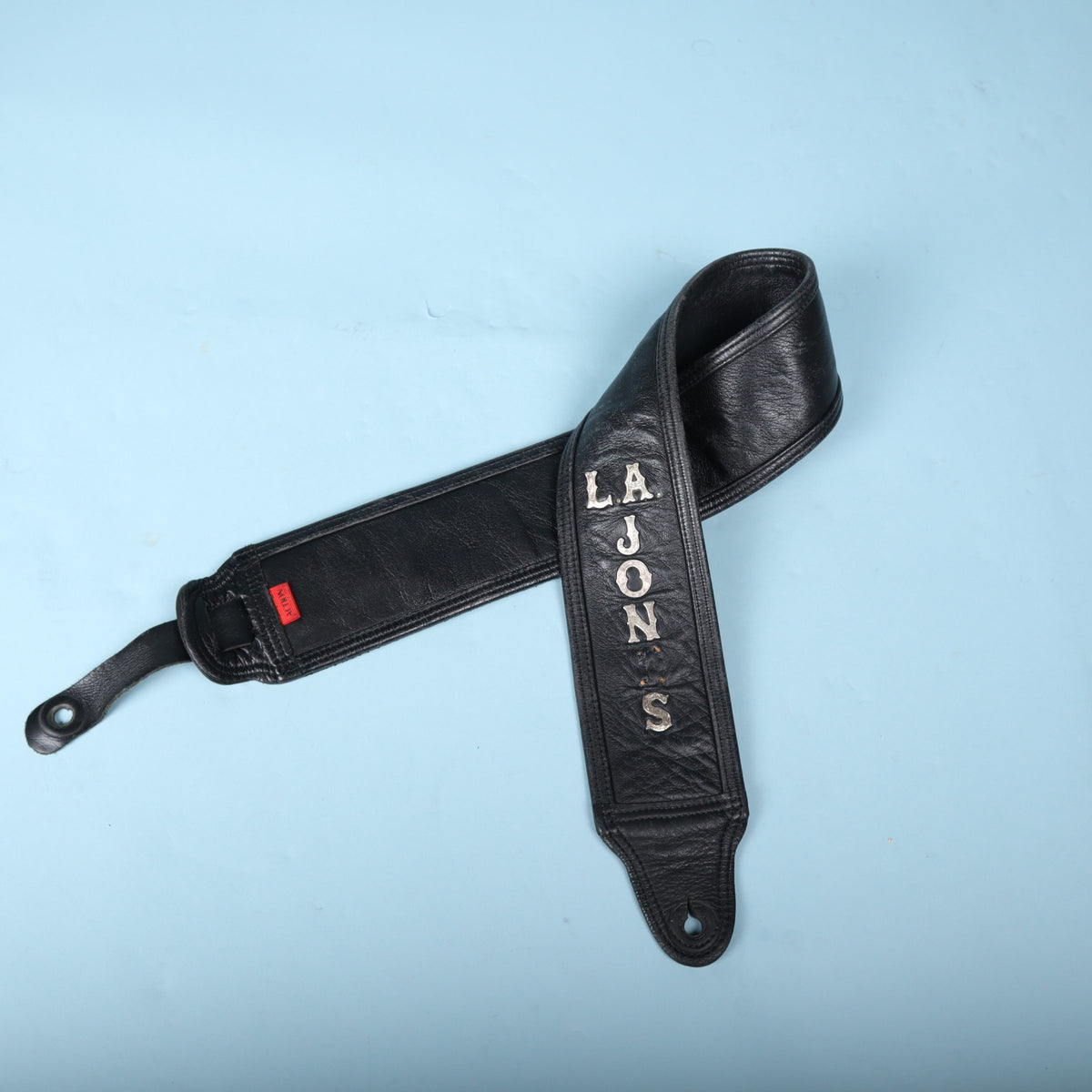 The Action leather bass strap loosely coiled, highlighting the front lettering and rear brand label.