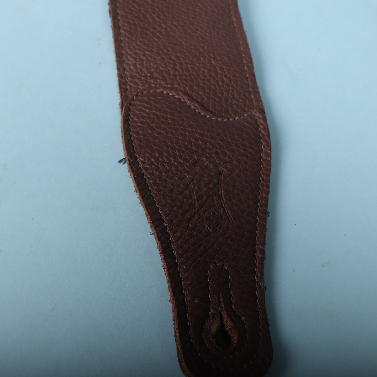 Macro detail of the embossed Levy's crest logo on the pebbled brown leather end