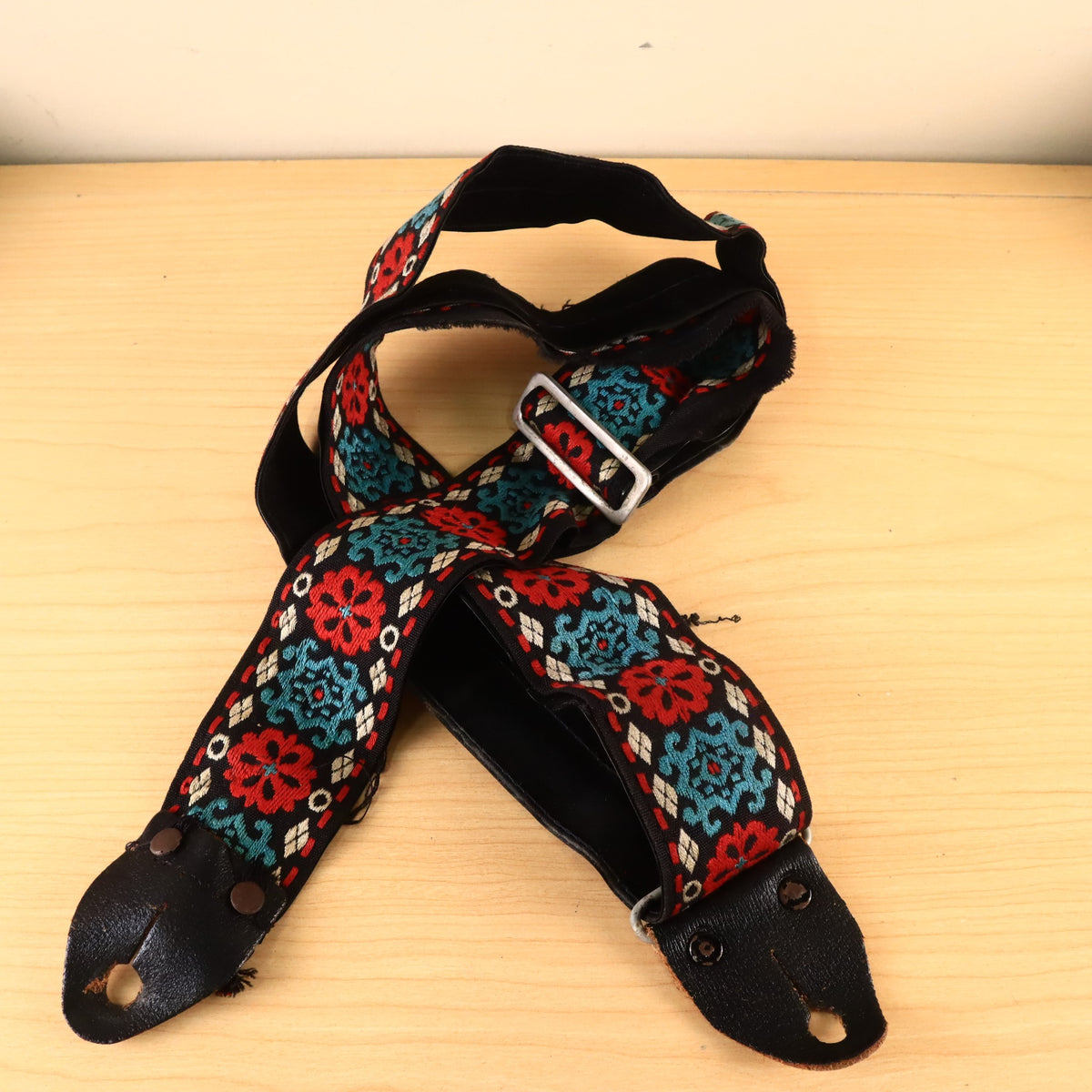 Overhead view of coiled Hootenanny guitar strap with leather end tabs.