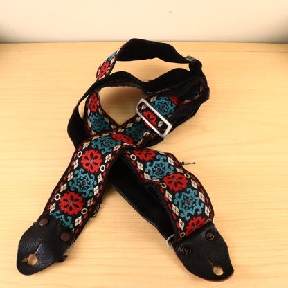 Overhead view of coiled Hootenanny guitar strap with leather end tabs.