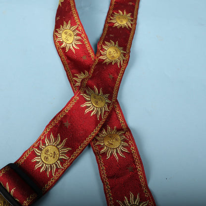 Detailed close-up of embroidered gold sun faces on red ribbon