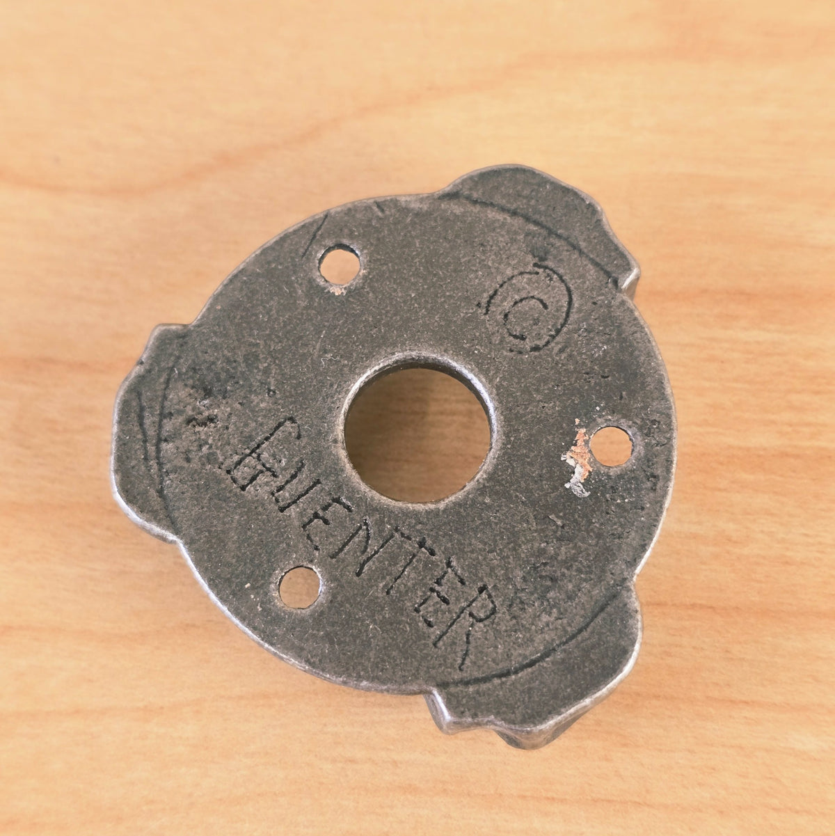 Close-up of the reverse side of the Gunther guitar plate displaying the stamped GUENTER mark.