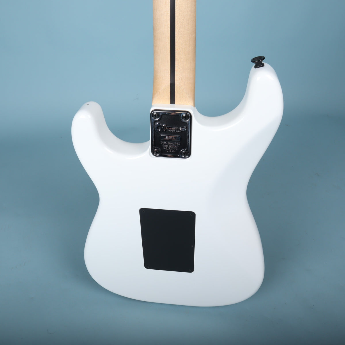 Angled back view of white contoured body and tremolo cavity cover.