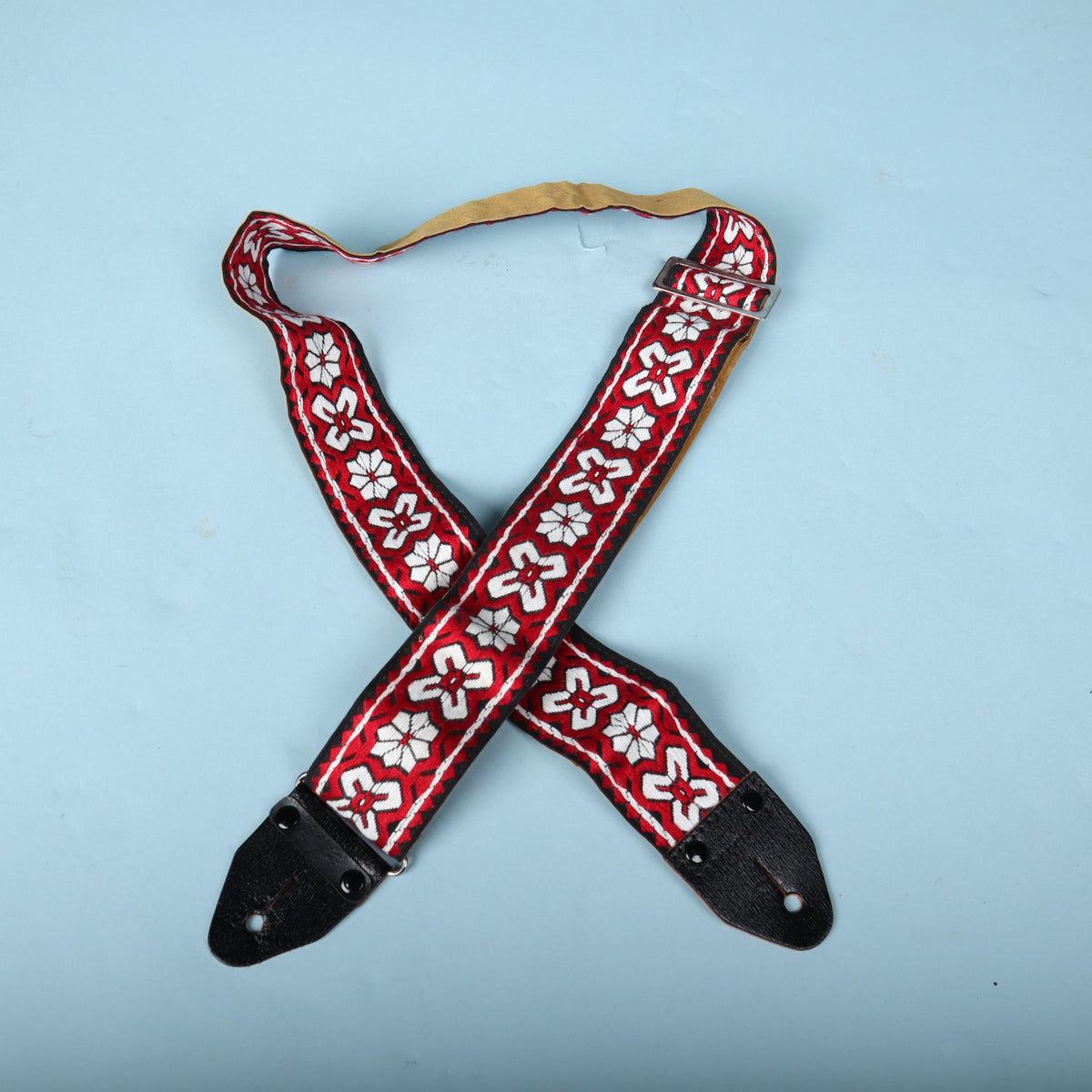 Front view of the 1960s woven guitar strap laid flat showing the red and white floral jacquard pattern