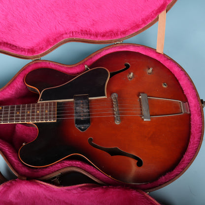 Close-up of the thin hollowbody electric guitar body inside the pink plush case lining for reference