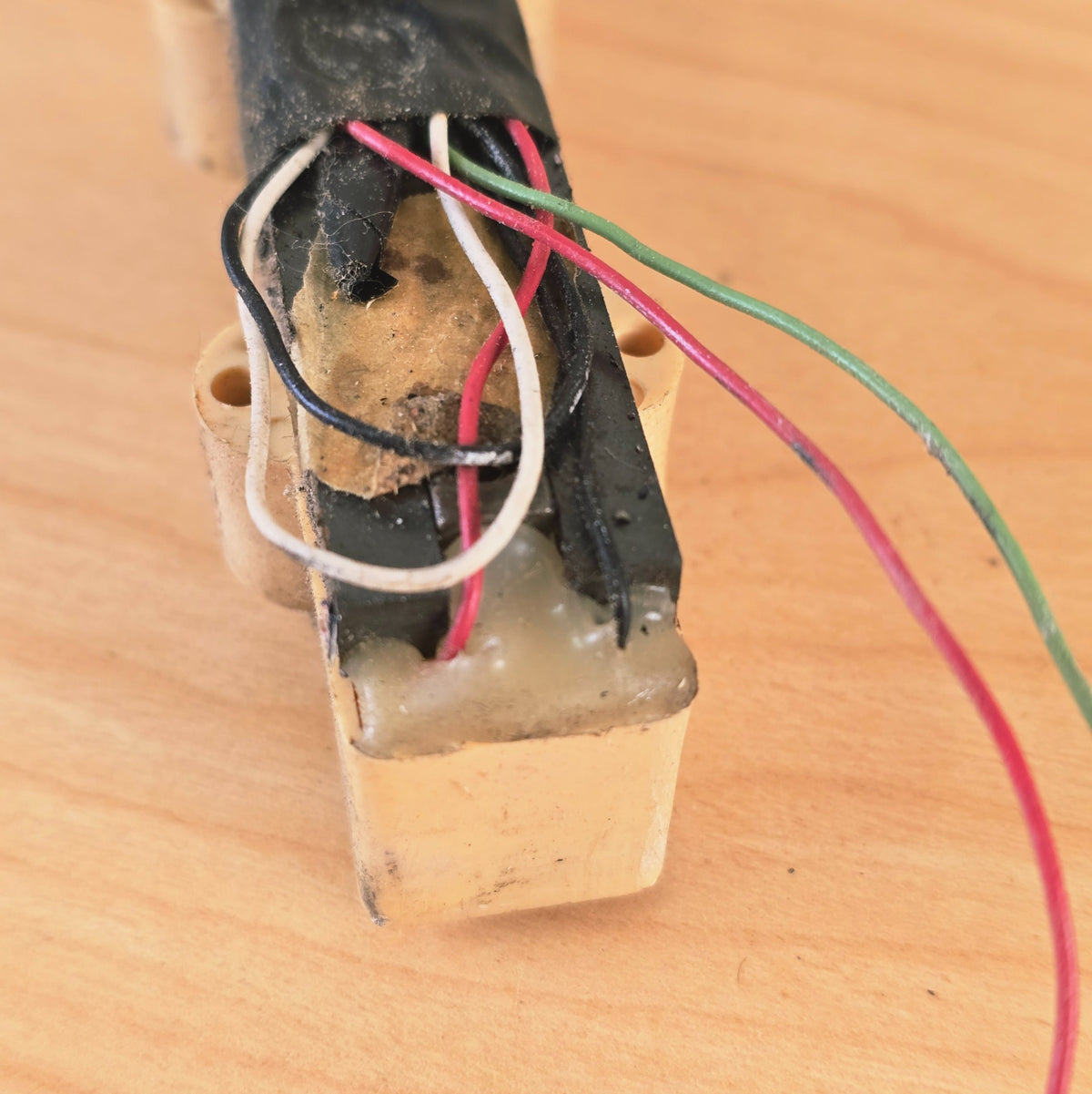 End view detail of bass pickup showing wire exit point and epoxy potting.