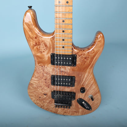 Close-up of burl top guitar body with black hardware and control switches.