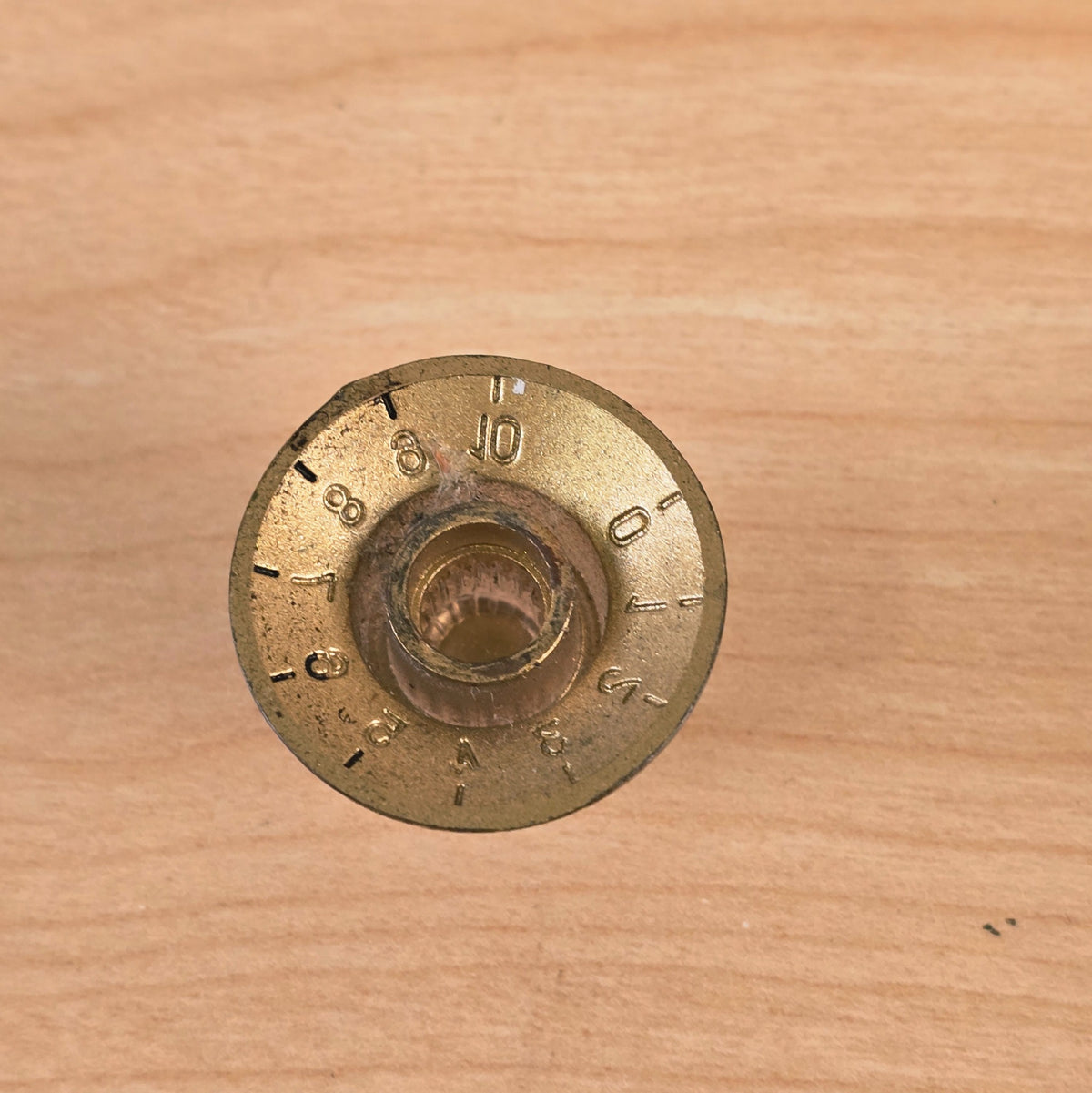 Underside view of gold top hat guitar control knob revealing splined shaft hole