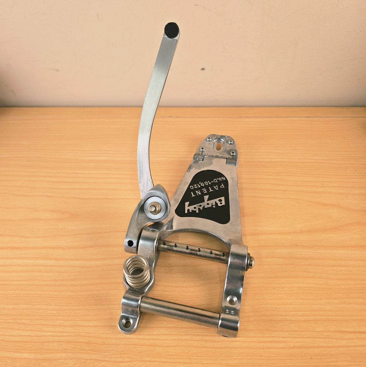Full top-down view of the Bigsby vibrato tailpiece on a wooden surface.