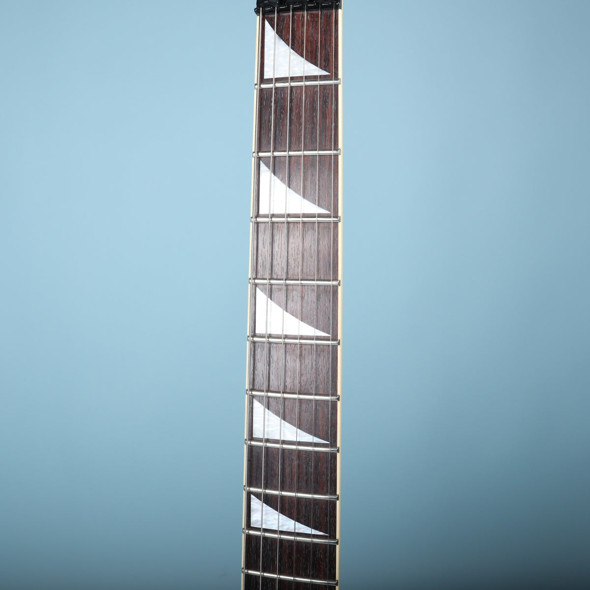 Close-up of fretboard showing rosewood grain, frets, and pearloid sharkfin inlays