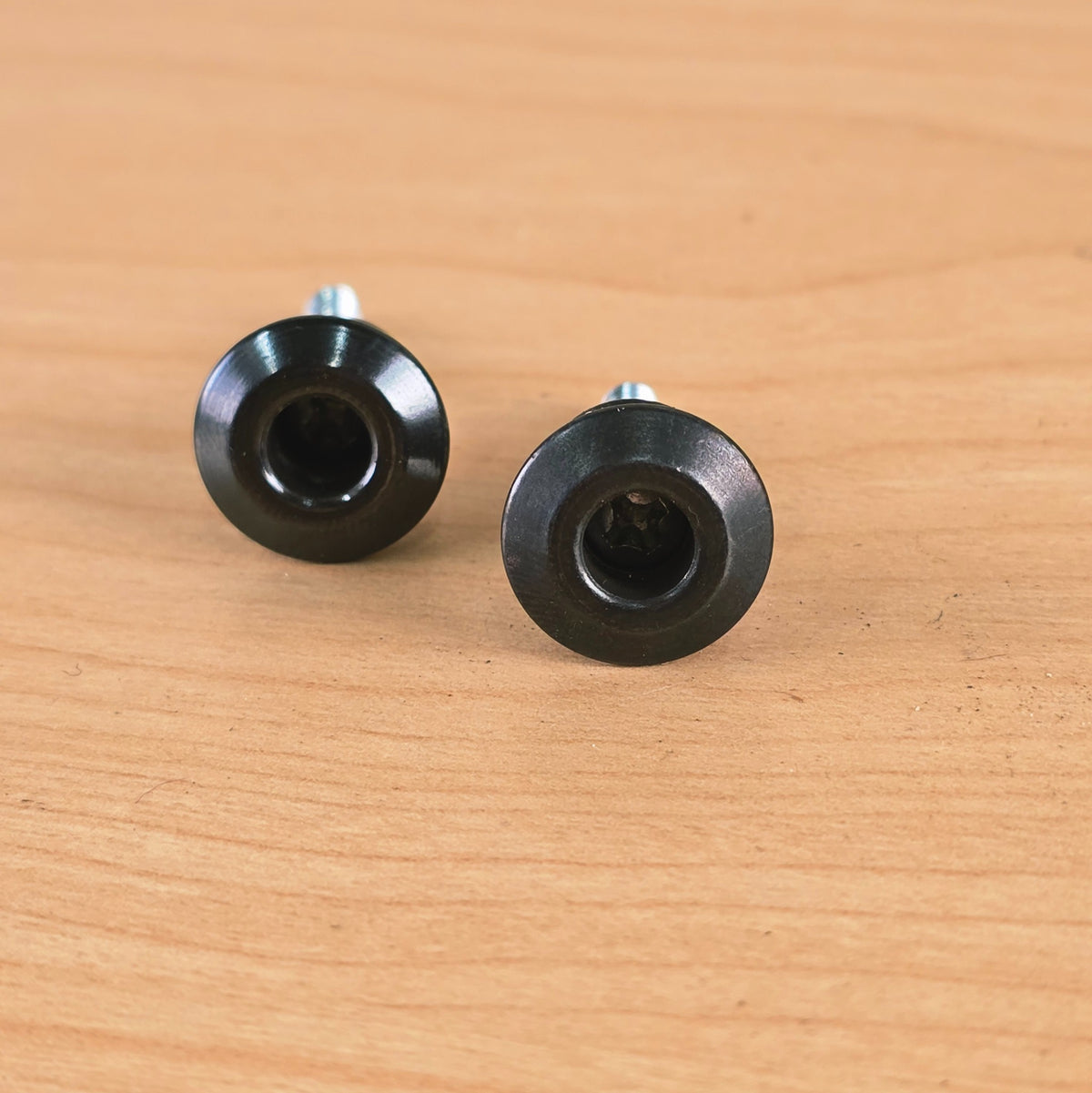 Top-down view into the recessed screw cavity of two black Dunlop Straplok buttons