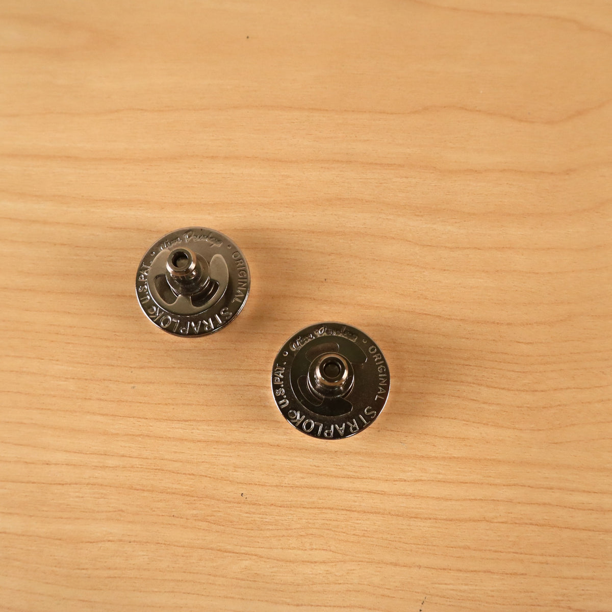 Top-down view of two Jim Dunlop Original Straplok quick-release strap attachments showing the engraved text.