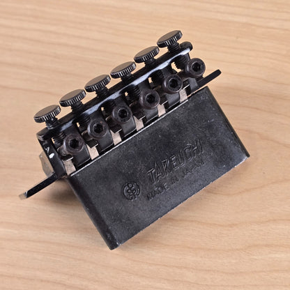 Angled view of tremolo block showing Takeuchi branding and logo