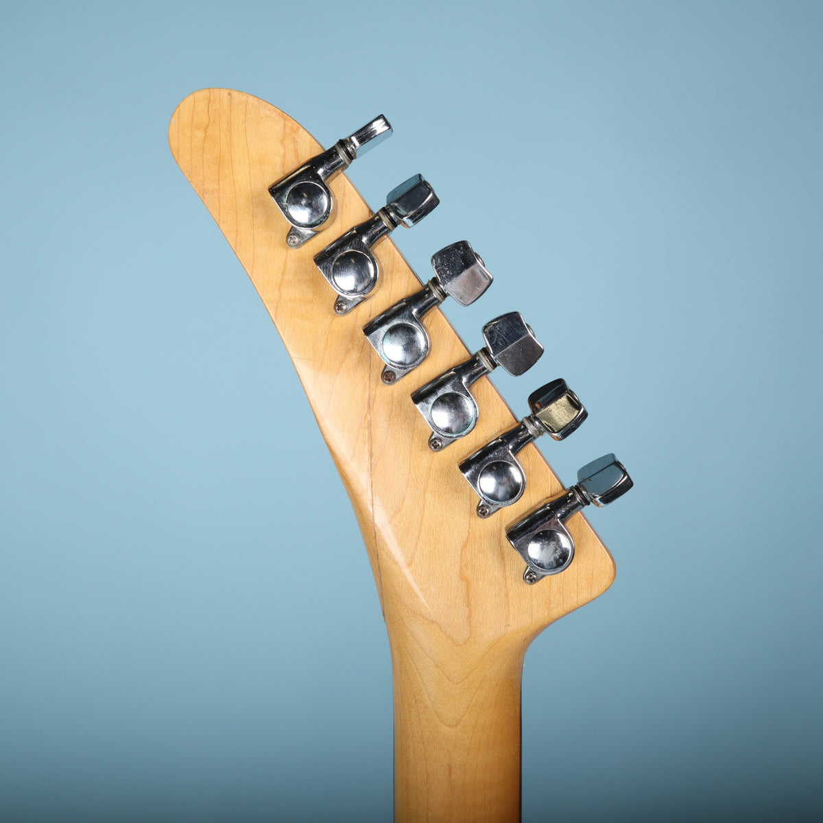 Rear view of the headstock showing six inline chrome tuning machines.
