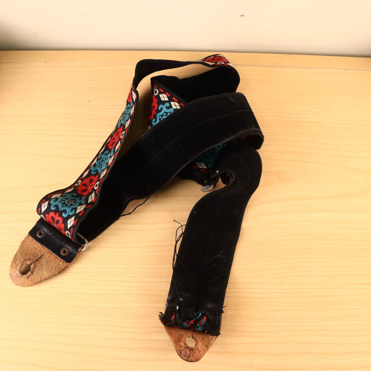 Overhead view of complete guitar strap showing fabric wear and leather ends.