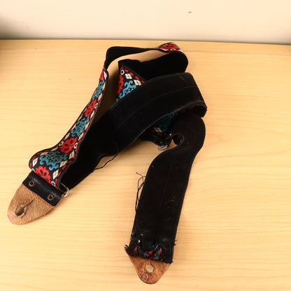 Overhead view of complete guitar strap showing fabric wear and leather ends.