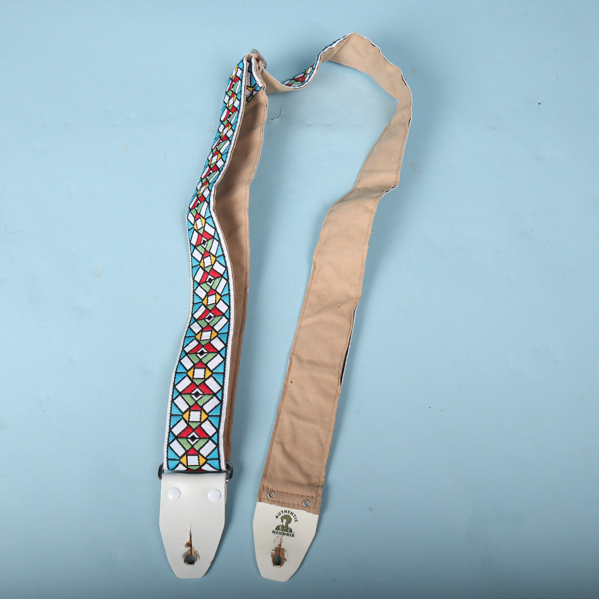 Authentic Hendrix guitar strap unfolded showing the length of the tan underside and jacquard face
